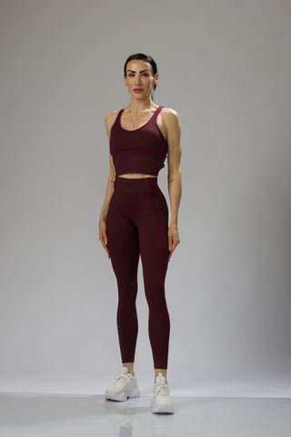 Back view of Reaux burgundy leggings with a crisscross open-back top, designed for movement and striking details.
