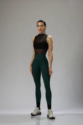 Reaux high-waisted performance leggings in green, styled with a sheer black mesh top, balancing boldness and elegance.
