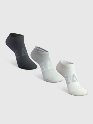 A set of three white, black, and gray athletic socks with reinforced cushioning and ribbed ankle support, featuring the Reaux logo.